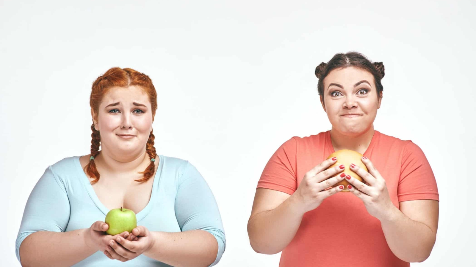 Funny picture of amusing chubby women on white background. One woman holding a sandwich, the other holding an apple.