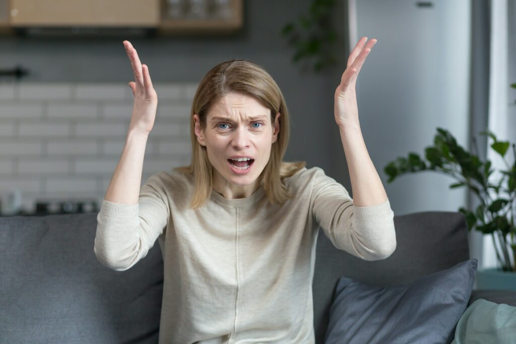 angry and frustrated woman talking on video call looking at webcam, angrily gesturing