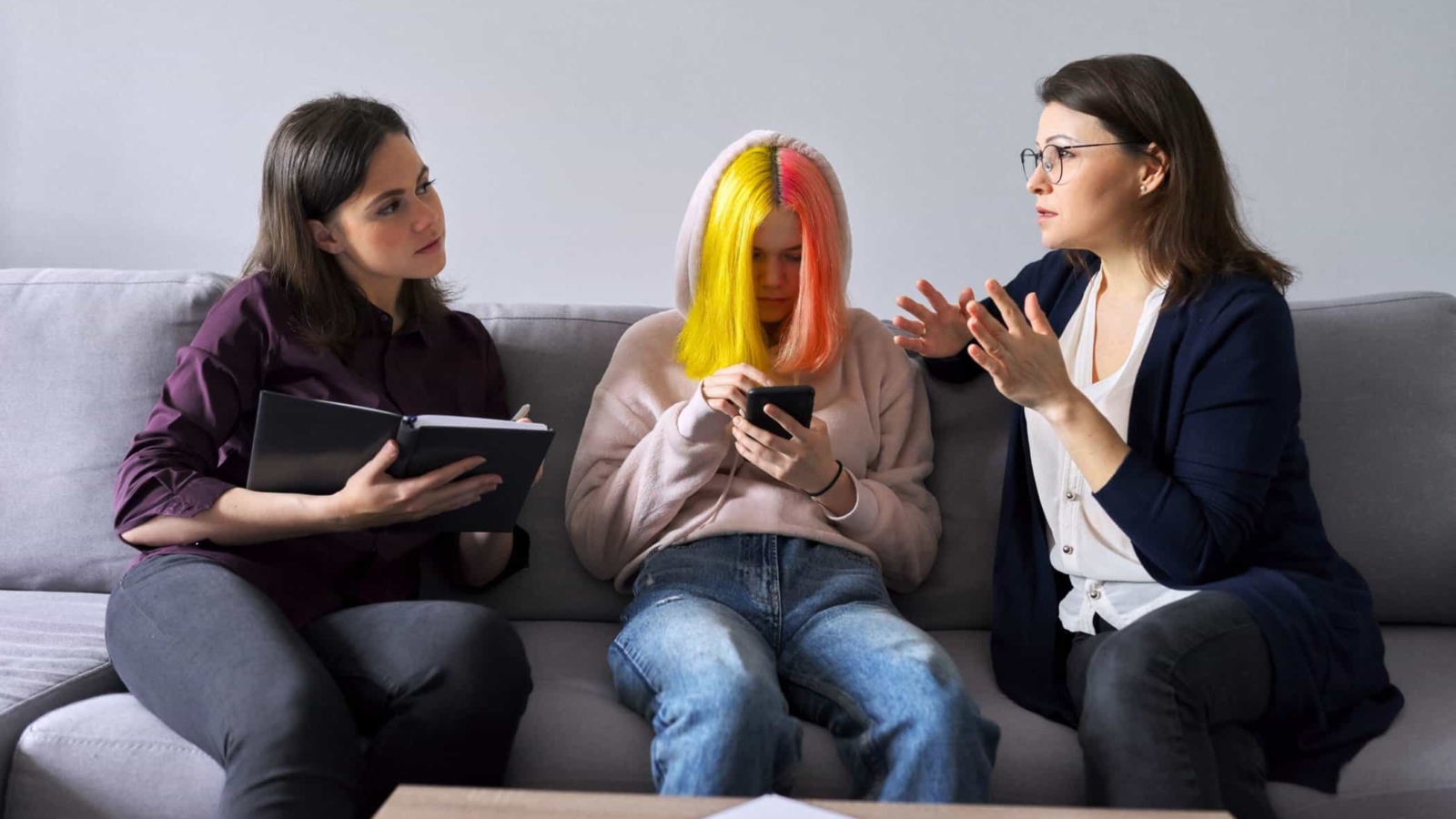 Family mother and teenage daughter in meeting with psychologist. Professional help, support, women are sitting in office on couch. Psychology, therapy, adolescence, relationship parent child teenager