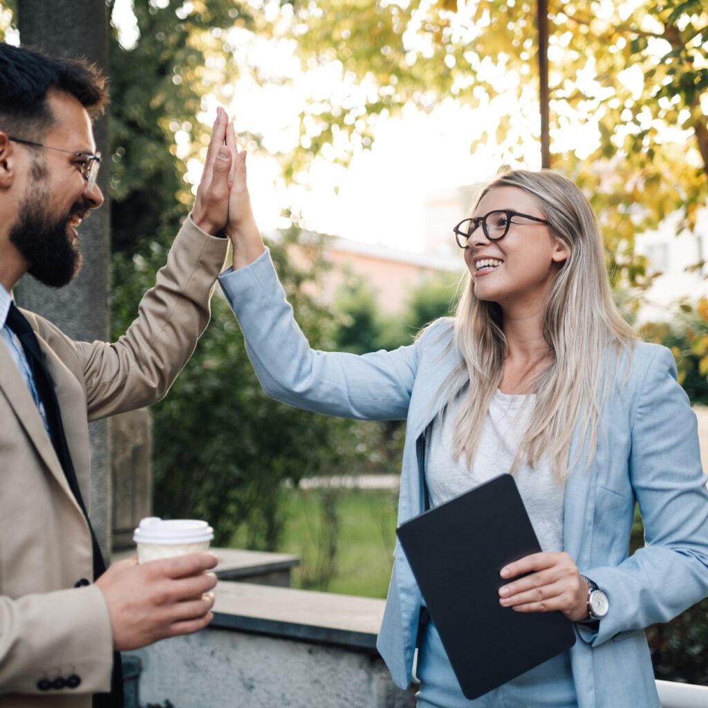 Business people giving high five outdoors after successful business deal