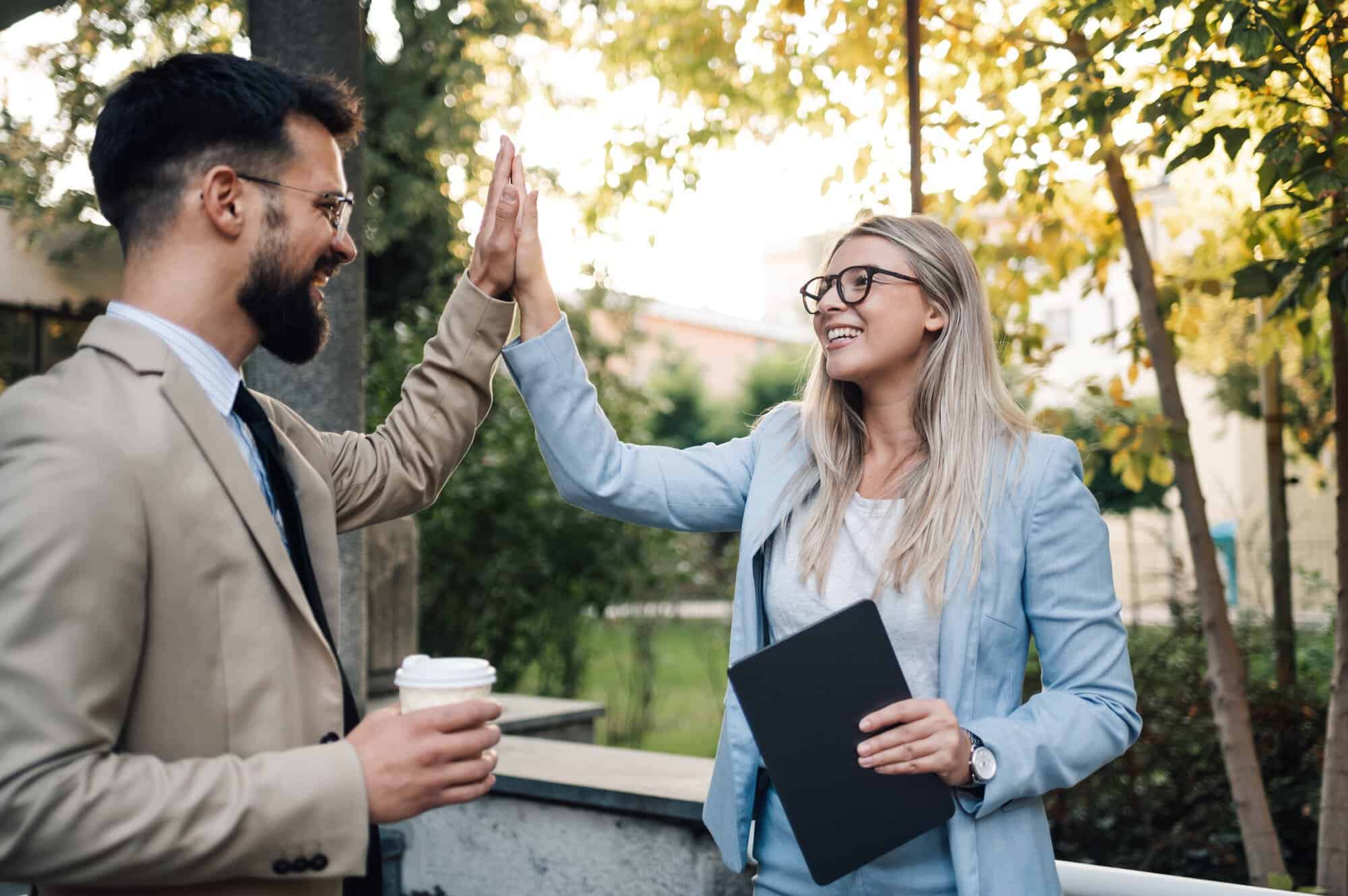 Business people giving high five outdoors after successful business deal